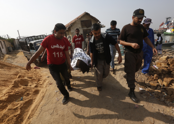 Workers carry a body to the ambulance.