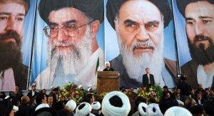 Iranian President Hassan Rouhani delivers a speech under portraits of Iran's supreme leader, Ayatollah Ali Khamenei (Center L) and Iran's founder of the Islamic Republic, Ayatollah Ruhollah Khomeini (Center R), on the eve of the 25th anniversary of the Islamic revolutionary leader Ayatollah Ruhollah Khomeini's death, at his mausoleum in a suburb of Tehran